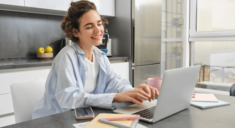 Retrato de uma jovem empresária que trabalha em casa olhando para o laptop e sorrindo, representando uma pessoa fazendo imposto de renda Foto: benzoix no Freepik