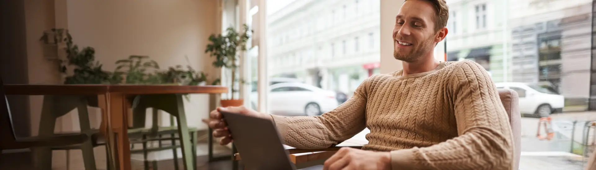 Retrato de um jovem profissional trabalhando sentado em um café com um laptop bebendo café e trabalhando online como freelancer usando o espaço de coworking para fazer seu trabalho. Retratando uma pessoa lendo dicas para anfitrião Foto: benzoix no Freepik